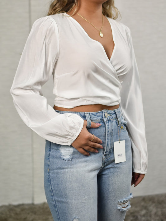 Blusa blanca de manga larga con lazo en la parte delantera